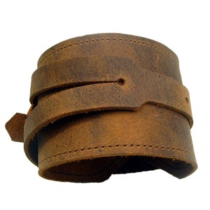 Op de afbeelding: Een bruin leren armband met een verweerde afwerking en stiksels.