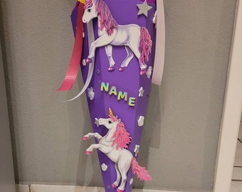 Könnte beinhalten: Lila-rosa Schultüte mit Einhorn-Motiv. Die Tüte hat ein weiß-rotes Band drumherum gebunden. Auf der Tüte steht "NAME".