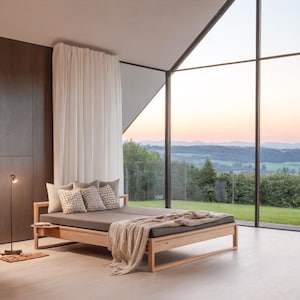 Peut inclure: Un canapé-lit en bois moderne avec un coussin gris et des coussins décoratifs. Une couverture beige est drapée sur le lit. Le lit est dans une pièce avec de grandes fenêtres donnant sur un paysage verdoyant. Un lampadaire et une table de chevet en bois sont également visibles.