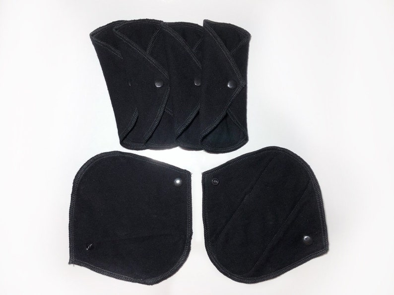 May include: Five black reusable cloth menstrual pads with snaps. Two additional pads are shown separately.