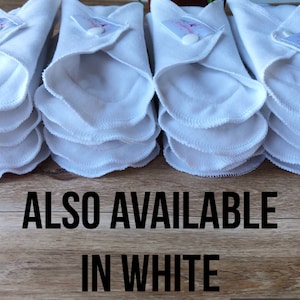 May include: A stack of white reusable cloth pads, folded and ready to use.  The text "ALSO AVAILABLE IN WHITE" is printed below the pads.