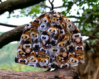 May include: A brown and black hat with a pattern of cartoon animal faces. The hat is made of fabric and has a white background.