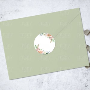 May include: A round sticker with a watercolor floral design in shades of pink, white, and green. The sticker is on a light green envelope.