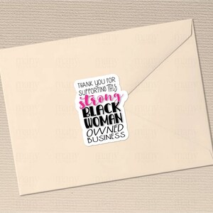 May include: A sticker with the text "Thank you for supporting this strong Black woman owned business" in black and pink lettering on a white background.