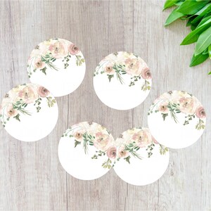 May include: Six round white paper labels featuring a watercolour floral design in shades of pink and green. The flowers are clustered at the top of each label.