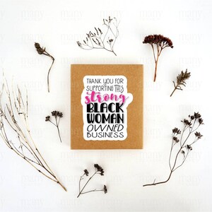 May include: A brown card with a white sticker that says "Thank you for supporting this strong Black woman owned business". The sticker has pink lettering for the word "strong".