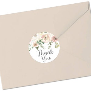 May include: A round thank you sticker featuring a watercolour floral design in shades of pink and white. The sticker has the text "Thank You" in grey lettering.