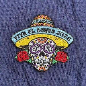 May include: Embroidered patch featuring a sugar skull wearing a sombrero. The skull has floral designs and the text "GIO OSE" on the eye sockets. The patch includes the text "VIVA EL GONZO 2026" and two red roses.