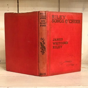 May include: A red hardcover book titled "Riley Songs O'Cheer" by James Whitcomb Riley. The book features a small illustration of a bird on a branch on the spine.