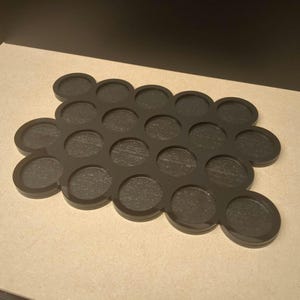 Peut inclure: Un plateau noir avec une forme organique distinctive, comportant de multiples cavit&eacute;s circulaires. Le plateau pr&eacute;sente de nombreuses empreintes circulaires, parfaites pour contenir de petits objets. La couleur sombre et le design sugg&egrave;rent une esth&eacute;tique moderne.