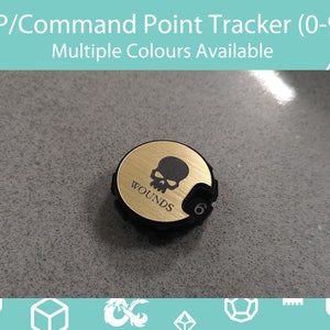Op de afbeelding: Een zwarte en gouden HP/Command Point Tracker met de tekst "WOUNDS" en een schedelafbeelding. De tracker heeft een draaiknop met het nummer 6. De tekst "HP/Command Point Tracker (0-9) Multiple Colours Available" staat bovenaan.