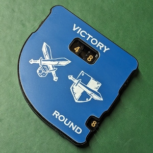 May include: A blue and black game counter featuring the words "VICTORY" and "ROUND" in white. The counter displays the numbers "48" and "8". White illustrations of swords and a shield are also present.