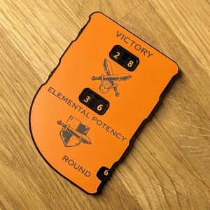 May include: An orange game tracker with black text and graphics. The tracker has three dials for Victory, Elemental Potency, and Round. The Victory dial shows 28, the Elemental Potency dial shows 36, and the Round dial shows 6.