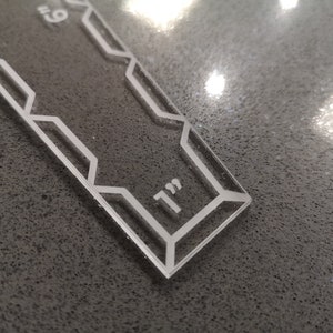 May include: A clear acrylic ruler with a geometric design and the text "9" and "1" in white. The ruler is approximately 9 inches long.