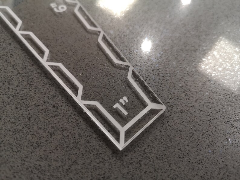 May include: A clear acrylic ruler with a geometric design and the text "9" and "1" in white. The ruler is approximately 9 inches long.