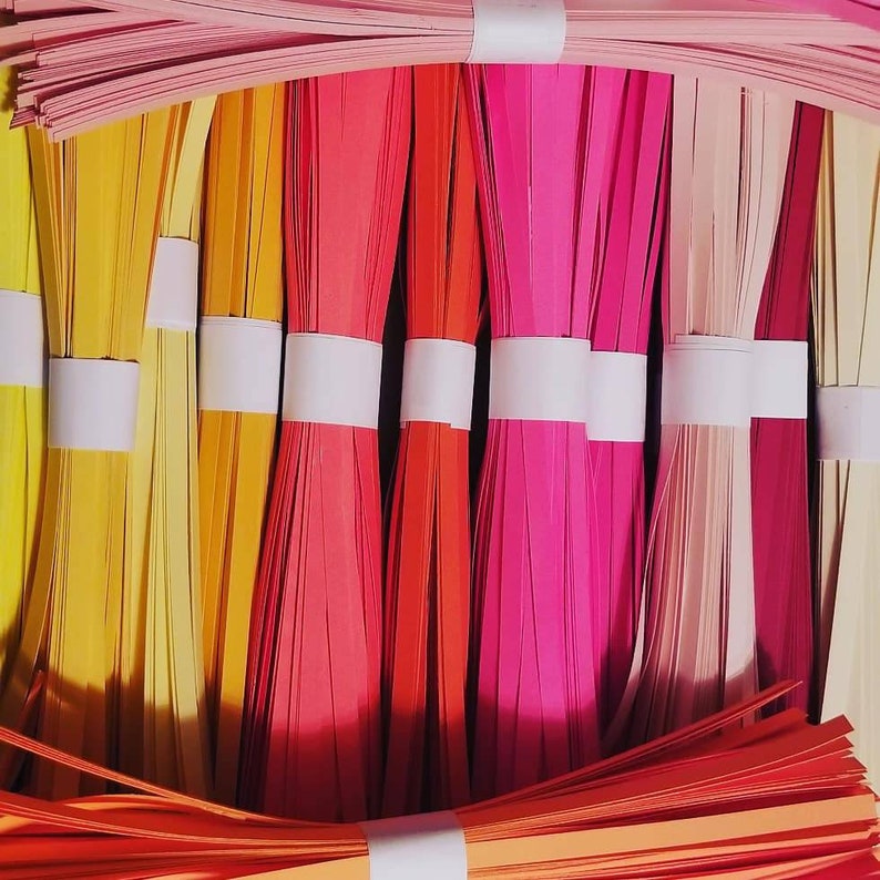 Puede incluir: Surtido de tiras de papel de colores en varios tonos de amarillo, naranja, rojo, rosa y melocot&oacute;n. Las tiras est&aacute;n agrupadas y atadas con una cuerda blanca.