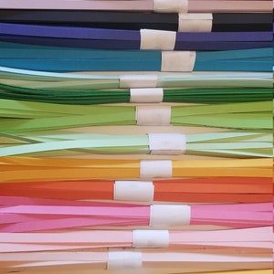 Puede incluir: Una pila de tiras de papel de colores, cada paquete est&aacute; atado con una etiqueta blanca. Los colores incluyen negro, marr&oacute;n, morado, rosa, azul, verde, amarillo, naranja, rojo y blanco.