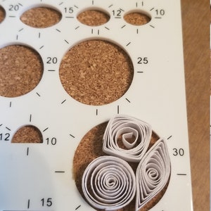 Puede incluir: Plantilla de pl&aacute;stico blanco con varias formas y tama&ntilde;os para manualidades. La plantilla tiene n&uacute;meros impresos en ella, incluyendo 5, 10, 12, 15, 20, 25 y 30. Hay tres formas de quilling de papel blanco en el centro de la plantilla.