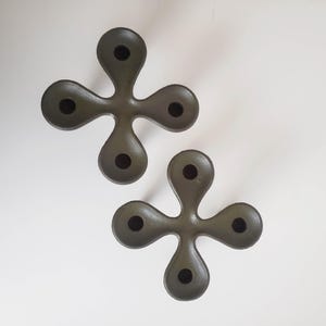 以下が含まれることがあります： 4つのキャンドルを置くことができる、濃い緑色の金属製のキャンドルホルダーが2つ。ホルダーは四つ葉のクローバーの形をしています。