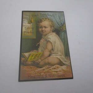 May include: Vintage advertisement for "Prof. Horsford's Baking Powder" featuring a baby reading a book. The image has a soft, pastel color palette with text that reads "Healthful & Nutritious". The baby is wearing a white dress.