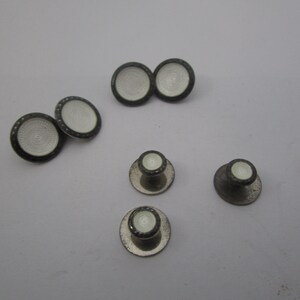 May include: Set of five silver cufflinks with white enamel. Two cufflinks have a circular design and three cufflinks have a dome shape.