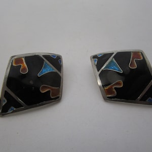 May include: A pair of silver earrings with black enamel and geometric designs in orange and blue.