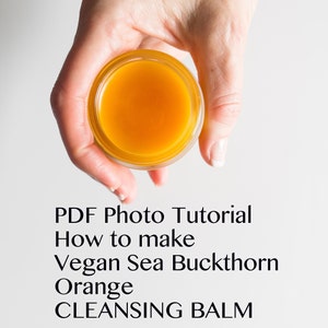 May include: A hand holds a small glass jar filled with a bright orange, thick balm. The jar is labeled "PDF Photo Tutorial How to make Vegan Sea Buckthorn Orange CLEANSING BALM".