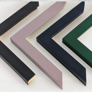 May include: Four L-shaped picture frame corners arranged in a row. The frames are finished in solid matte colours including black, dusty rose, dark navy blue, and forest green. Each frame corner features a clean, angled mitered edge design.