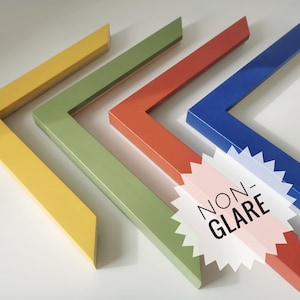 May include: Four L-shaped picture frame corners in yellow, olive green, terracotta, and blue. A white starburst sticker with the black text NON-GLARE is placed over the terracotta frame corner, indicating the finish of the frame material.