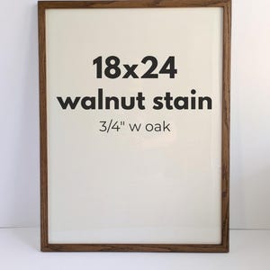May include: A rectangular picture frame with a walnut stain finish and a 3/4 inch wide oak border. The center of the frame displays the black text 18x24, walnut stain, and 3/4 inch w oak printed on a plain off-white background.
