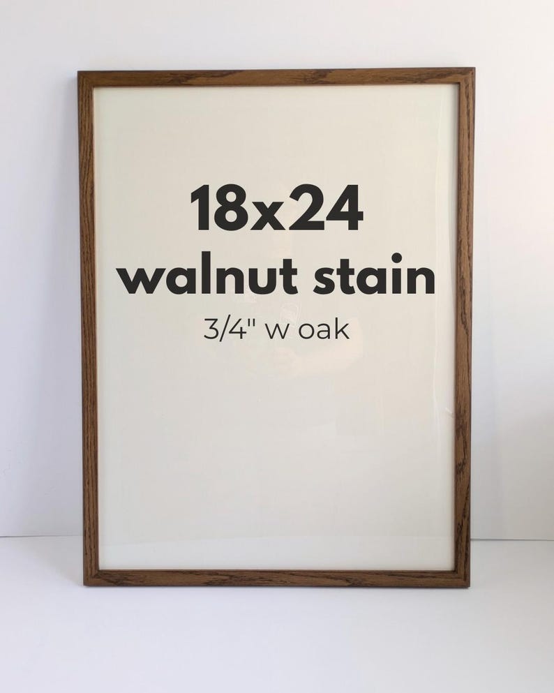 May include: A rectangular picture frame with a walnut stain finish and a 3/4 inch wide oak border. The center of the frame displays the black text 18x24, walnut stain, and 3/4 inch w oak printed on a plain off-white background.