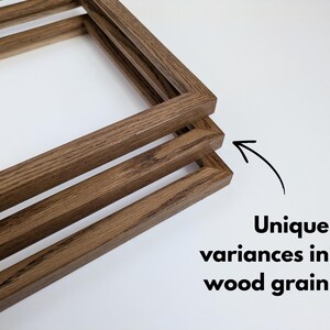 May include: Three rectangular wooden frames stacked at an angle, featuring a medium brown finish with visible natural wood grain patterns. An arrow points to the frames with the text: Unique variances in wood grain.