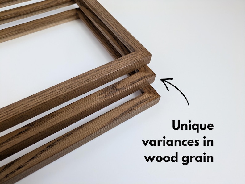 May include: Three rectangular wooden frames stacked at an angle, featuring a medium brown finish with visible natural wood grain patterns. An arrow points to the frames with the text: Unique variances in wood grain.