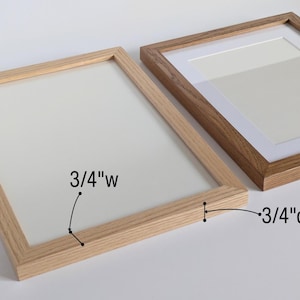 May include: Two rectangular wooden picture frames with a light wood grain finish. The frame on the left features a 3/4 inch width and a 3/4 inch depth as indicated by labels. The frame on the right includes a white mat board insert.