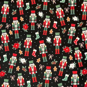 May include: Black fabric with a repeating pattern of Christmas nutcrackers in red, green, and gold. The design also includes gingerbread men, poinsettias, stockings, and snowflakes. White polka dots are scattered throughout the design.