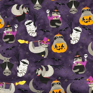 May include: Purple fabric with a repeating pattern of sloths dressed in Halloween costumes. The sloths are wearing witch hats, mummy costumes, and holding jack-o-lanterns. There are bats and stars in the background.