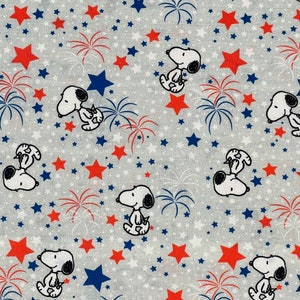 May include: A gray and white fabric with a repeating pattern of red and blue stars, fireworks, and cartoon dogs. The dogs are all wearing red, white, and blue hats.