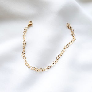 Puede incluir: Un brazalete de cadena dorada en forma de corazón con cierre de langosta.