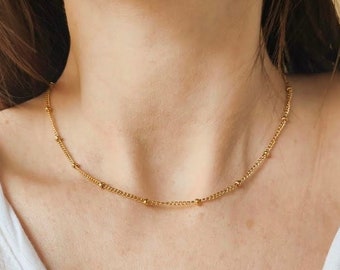 May include: A delicate gold chain necklace with small round beads.