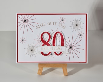 Carte d'anniversaire 3D pour un 80e anniversaire avec feux d'artifice, texte : Joyeux 80e anniversaire, couleurs rouge/marron clair