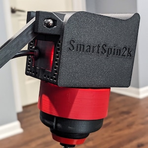 May include: A black SmartSpin2k turntable with a red base and a silver knob. The turntable is mounted on a tripod.