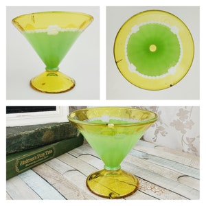May include: A green glass dessert dish with a yellow rim and white accents. The dish is on a wooden surface.