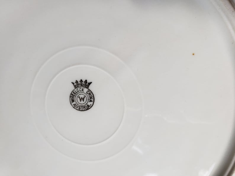 K&ouml;nnte beinhalten: Nahaufnahme einer wei&szlig;en Keramikplatte mit einem schwarz-wei&szlig;en Logo, das "Wheel ock China Austria" mit einer Krone &uuml;ber dem "W" lautet.
