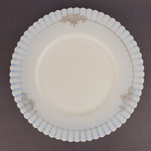 May include: A white ceramic plate with a blue and gold floral design. The plate has a scalloped edge.