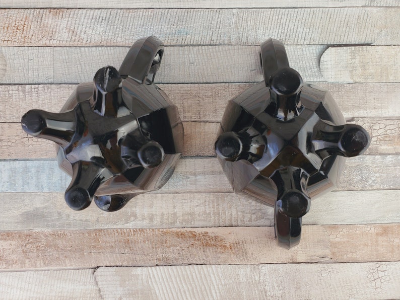 K&ouml;nnte beinhalten: Ein schwarzes Glas-Zucker- und Sahne-Set mit einem einzigartigen, geometrischen Design. Das Set ist aus schwarzem Glas gefertigt und hat eine gl&auml;nzende Oberfl&auml;che. Die Sahnegie&szlig;kanne und die Zuckerdose haben jeweils drei Beine.