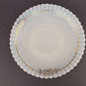 May include: A white milk glass saucer with a blue and gold rim and floral design.