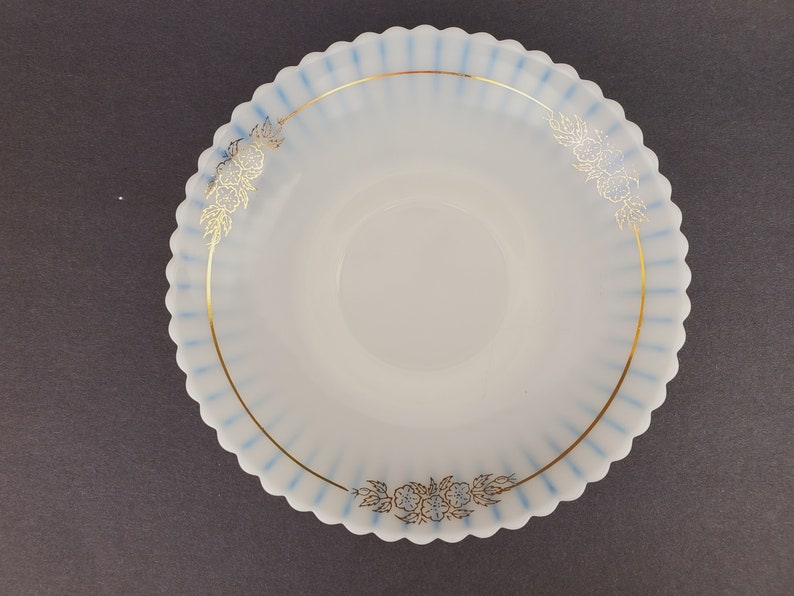 May include: A white milk glass saucer with a blue and gold rim and floral design.