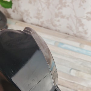 K&ouml;nnte beinhalten: Schwarze Teekanne aus Keramik mit gl&auml;nzendem &Uuml;berzug. Die Teekanne hat einen runden Korpus und einen Ausguss auf einer Seite. Auf der Unterseite der Teekanne befindet sich eine kleine Markierung mit der Aufschrift "633".