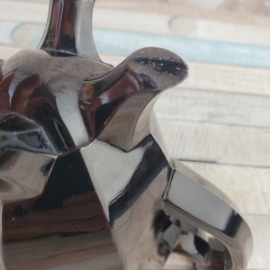 K&ouml;nnte beinhalten: Eine schwarze Glasteekanne mit geometrischem Design. Die Teekanne hat einen Griff und einen Ausguss. Die Teekanne ist aus gl&auml;nzendem, reflektierendem Material.