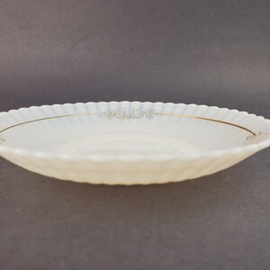 May include: A white, scalloped-edge saucer with a gold rim and a delicate floral design in gold.